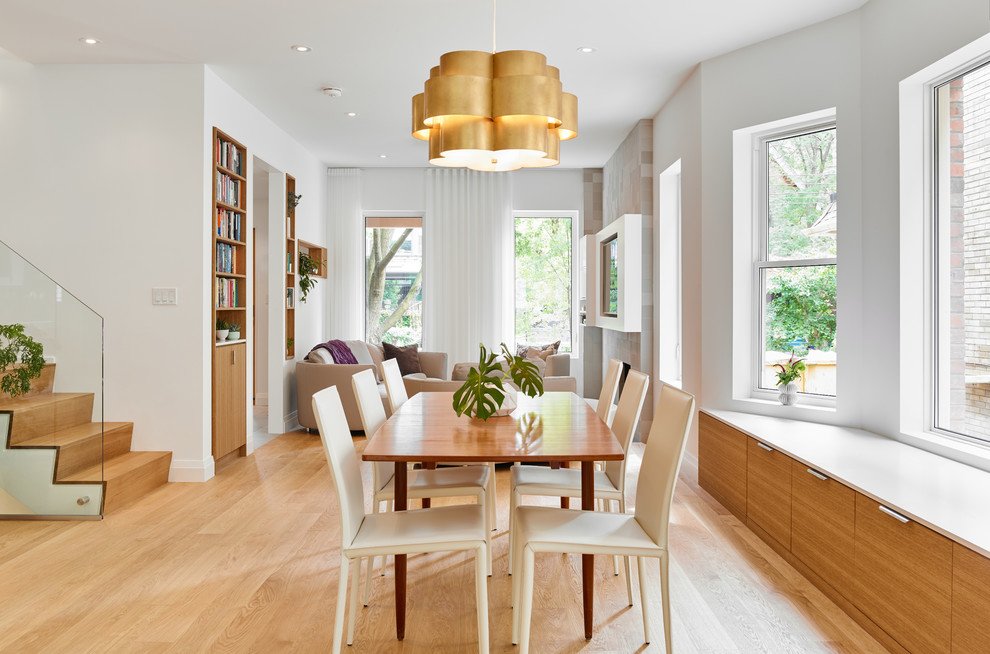 Стильный дизайн: кухня-столовая среднего размера в современном стиле с светлым паркетным полом, стандартным камином, фасадом камина из плитки, коричневым полом и белыми стенами - последний тренд