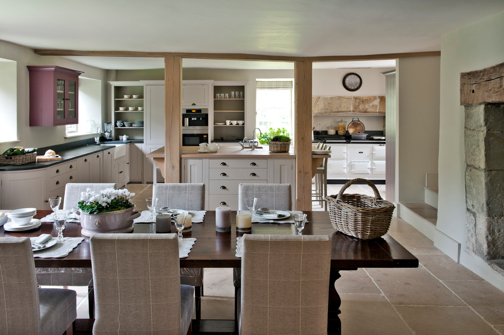 Свежая идея для дизайна: кухня-столовая в стиле кантри с белыми стенами и фасадом камина из камня - отличное фото интерьера