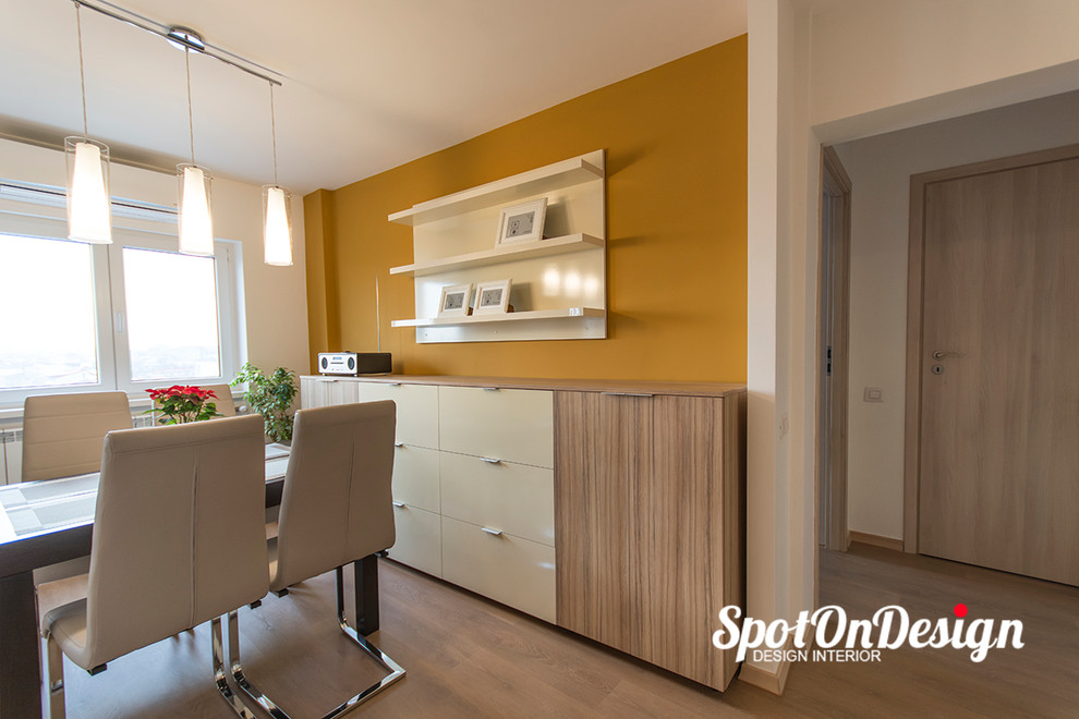 Réalisation d'une petite salle à manger ouverte sur la cuisine minimaliste avec un mur multicolore et parquet clair.