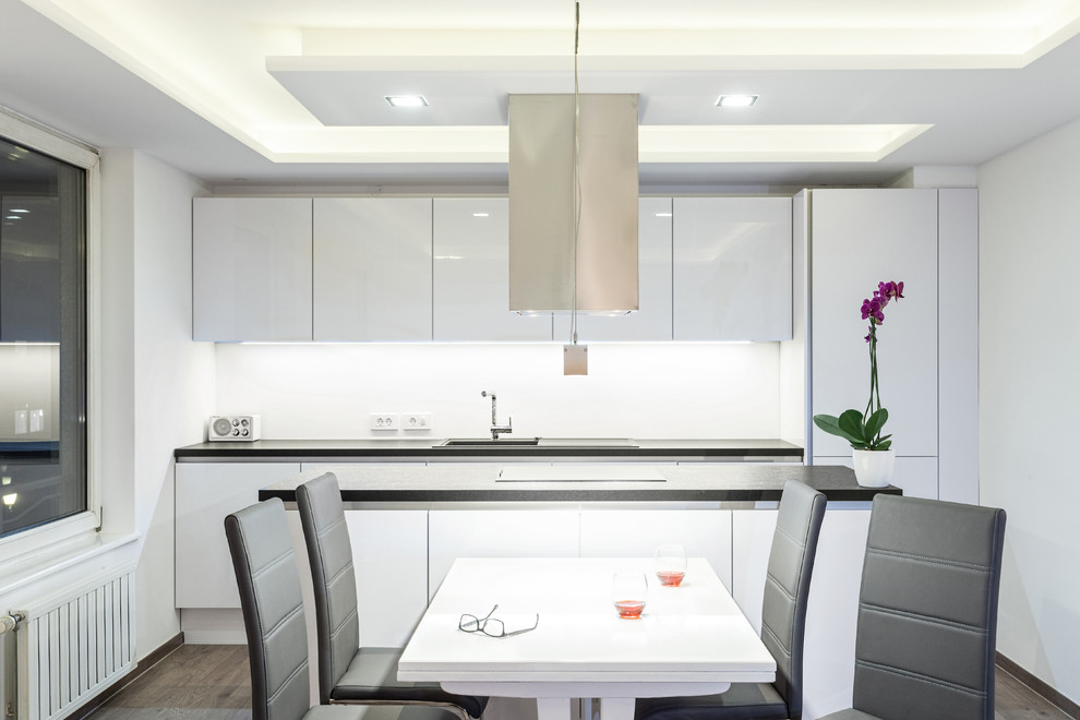 Idée de décoration pour une petite salle à manger ouverte sur la cuisine minimaliste avec un mur blanc, parquet foncé et un sol marron.