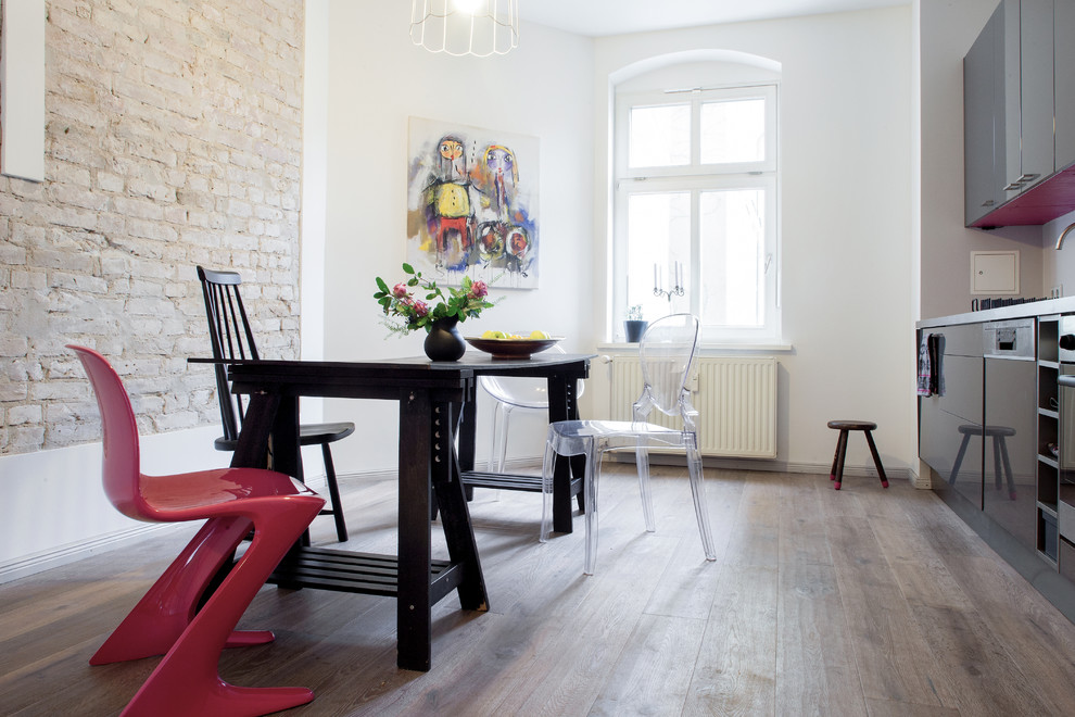 Inspiration pour une salle à manger ouverte sur la cuisine bohème de taille moyenne avec un sol en bois brun et un mur blanc.