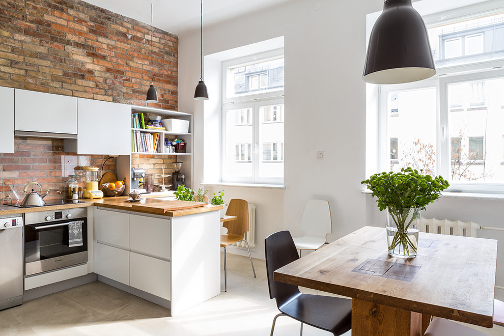 Cette photo montre une petite salle à manger ouverte sur la cuisine industrielle avec un mur blanc et sol en béton ciré.