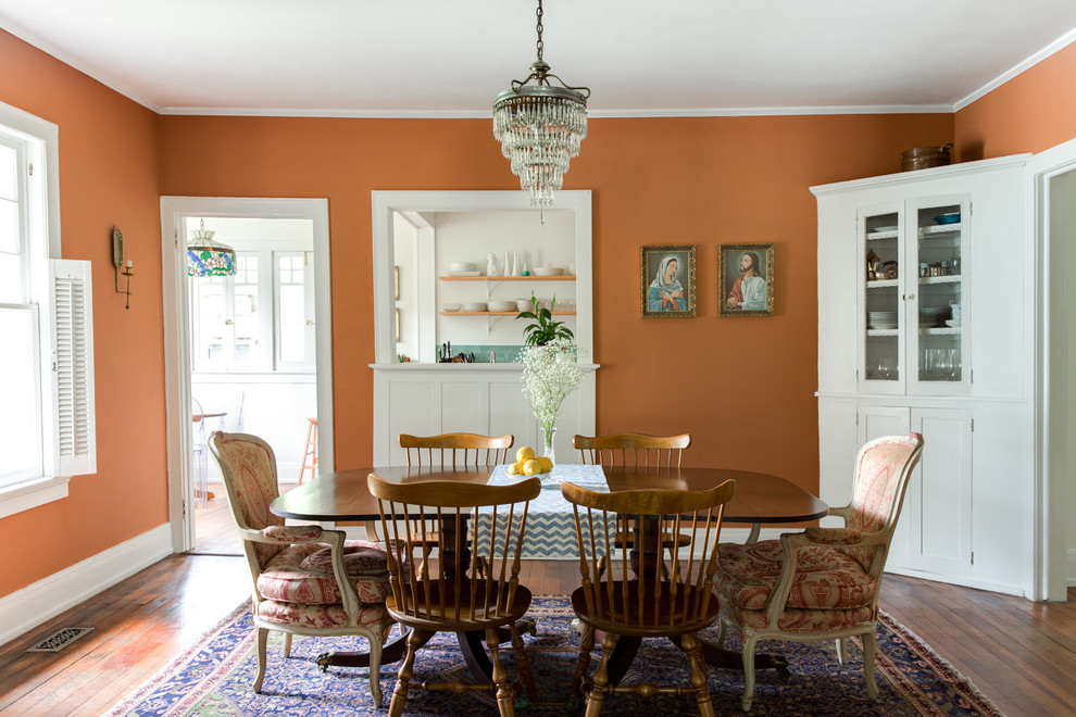 Idée de décoration pour une salle à manger tradition fermée avec un mur orange et un sol en bois brun.