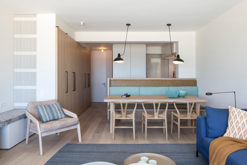 Bild på en minimalistisk matplats med öppen planlösning, med vita väggar, ljust trägolv och beiget golv