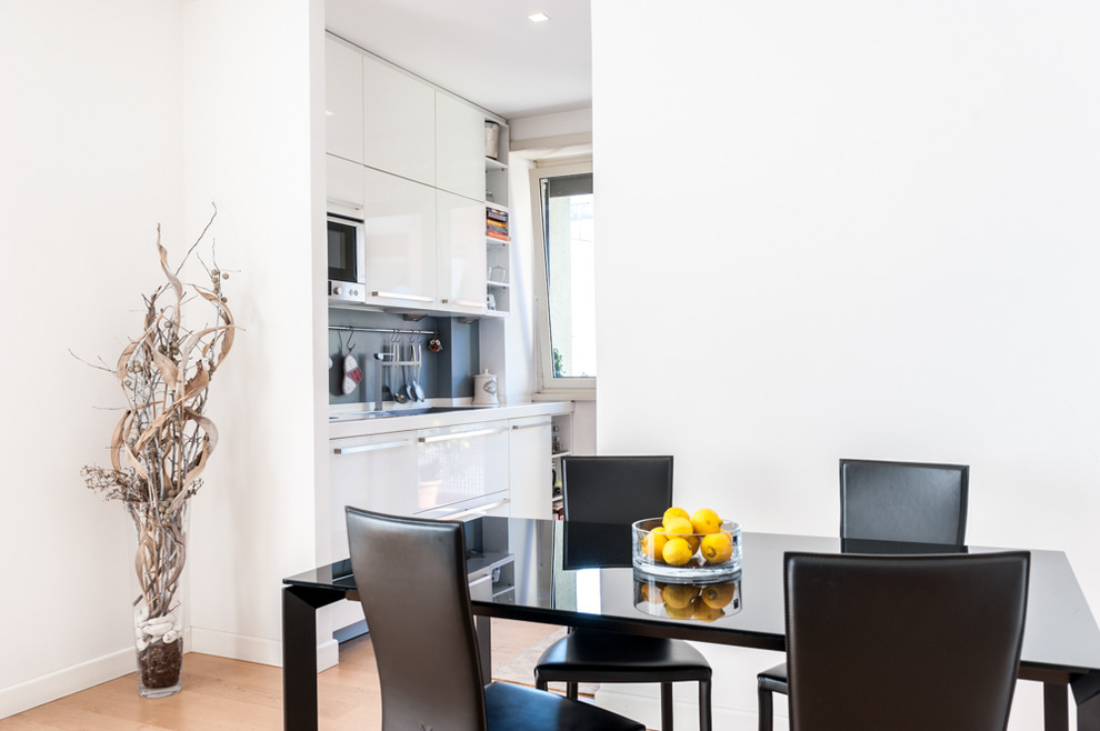 Idee per una sala da pranzo aperta verso la cucina minimal di medie dimensioni con pareti bianche, parquet chiaro, nessun camino e pavimento marrone
