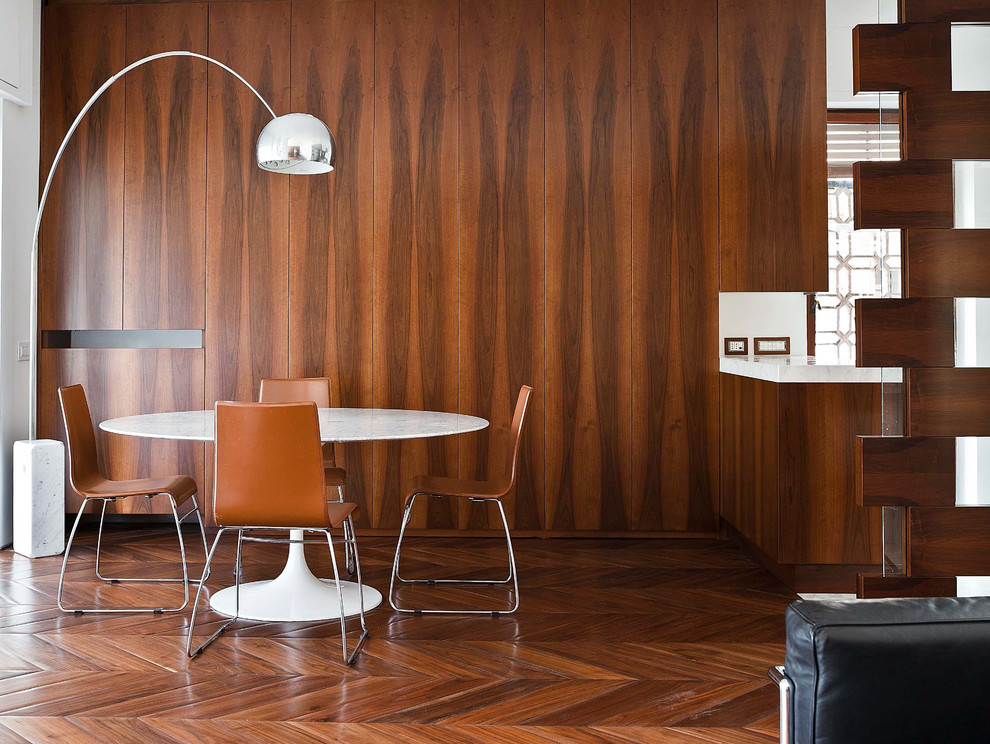 На фото: отдельная столовая в современном стиле с коричневыми стенами и паркетным полом среднего тона