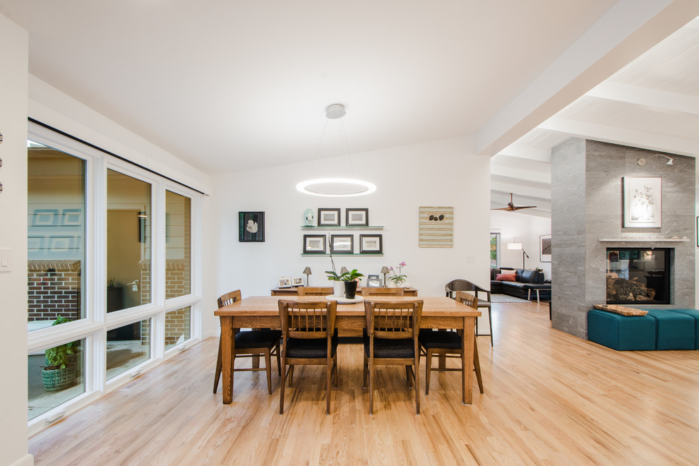Стильный дизайн: кухня-столовая среднего размера в стиле ретро с белыми стенами, светлым паркетным полом, двусторонним камином и фасадом камина из плитки - последний тренд
