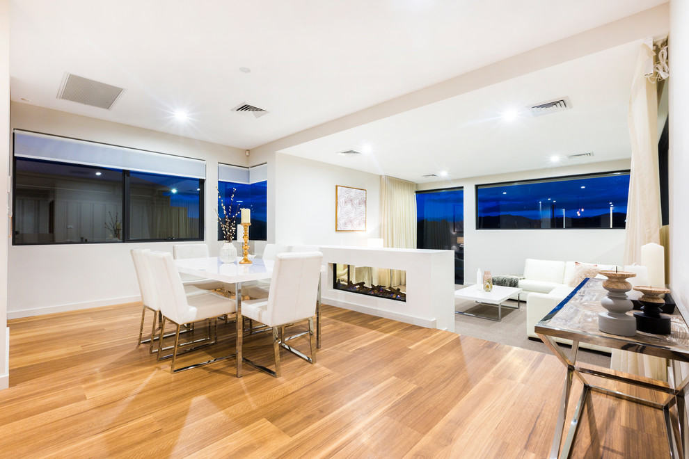 Offenes, Mittelgroßes Modernes Esszimmer mit weißer Wandfarbe, hellem Holzboden, Tunnelkamin, verputzter Kaminumrandung und orangem Boden in Canberra - Queanbeyan