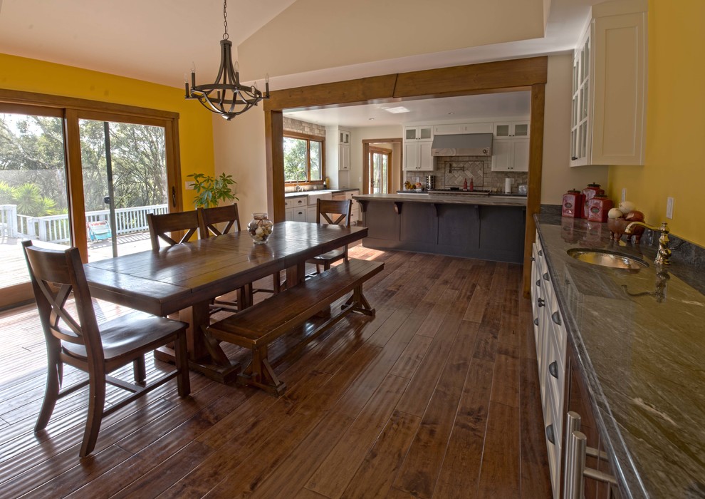 Idee per una sala da pranzo aperta verso la cucina stile americano di medie dimensioni con pareti gialle, parquet scuro e pavimento marrone