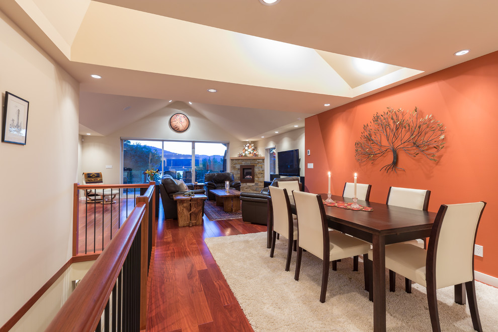 На фото: большая гостиная-столовая в современном стиле с паркетным полом среднего тона и оранжевыми стенами