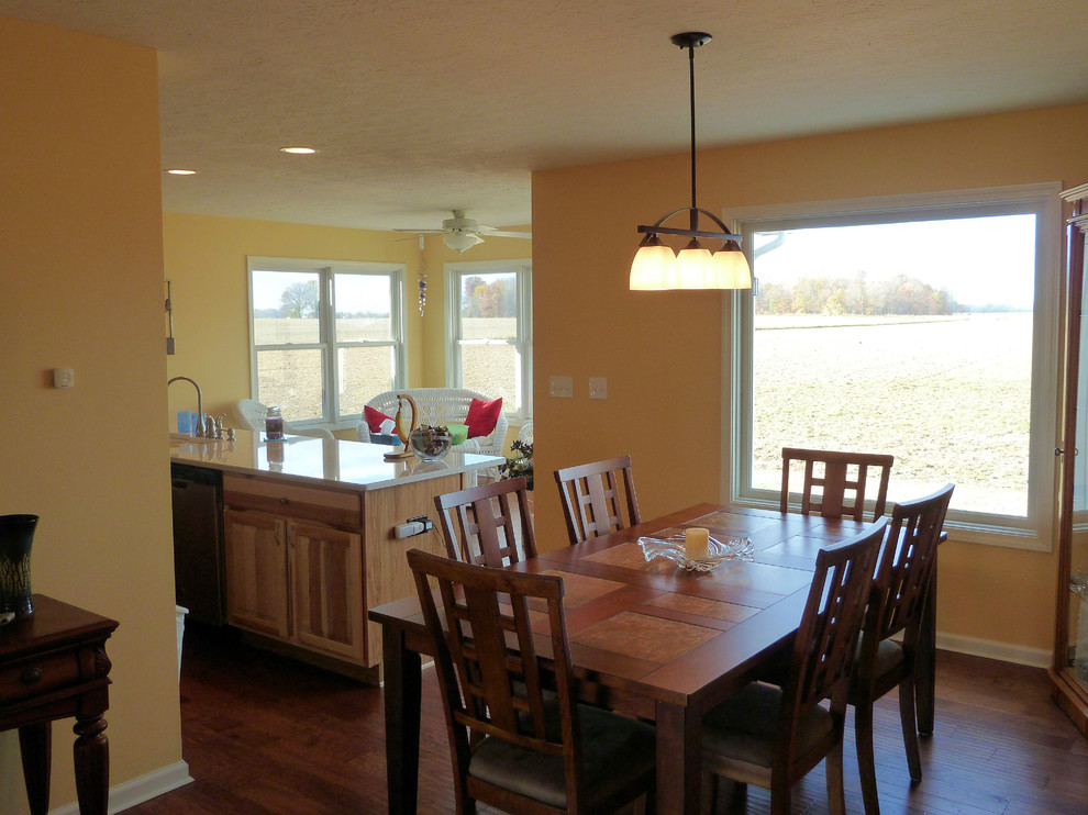 Foto di una sala da pranzo aperta verso la cucina country di medie dimensioni con pareti gialle, pavimento in legno massello medio e nessun camino