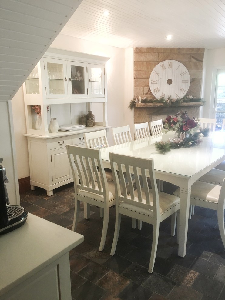 Источник вдохновения для домашнего уюта: кухня-столовая среднего размера в стиле кантри с белыми стенами, полом из сланца, угловым камином, фасадом камина из камня и разноцветным полом