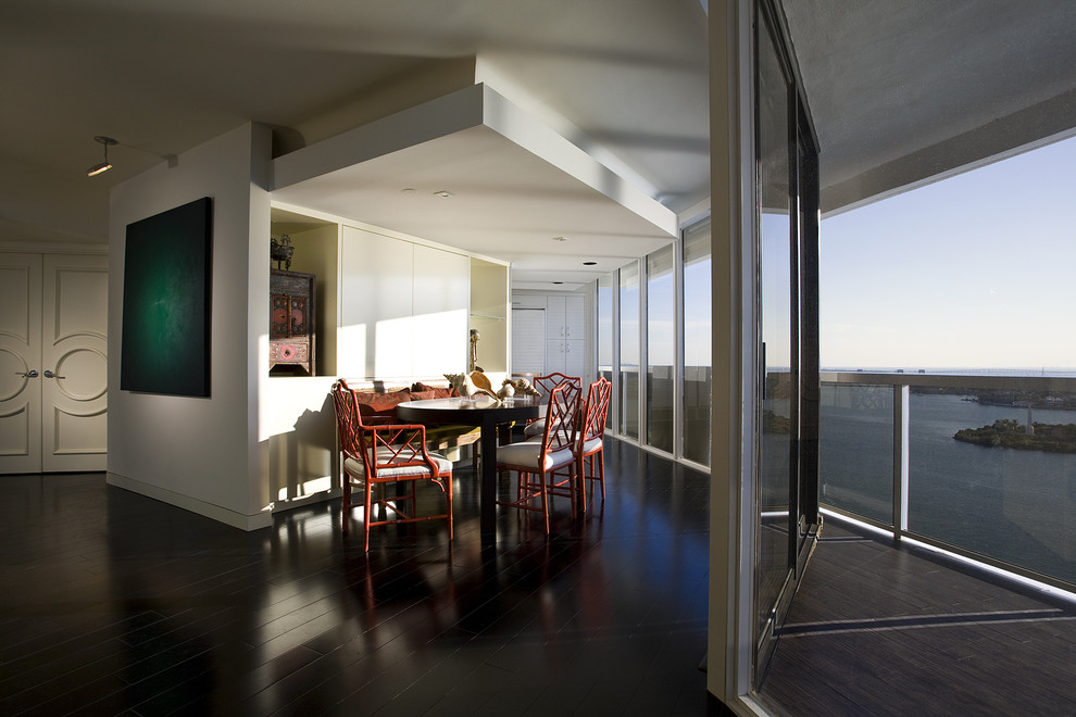 Example of a trendy dark wood floor and black floor dining room design in Miami with white walls