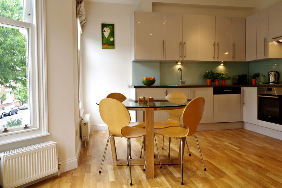 Design ideas for a small contemporary kitchen/dining room in London with white walls and light hardwood flooring.