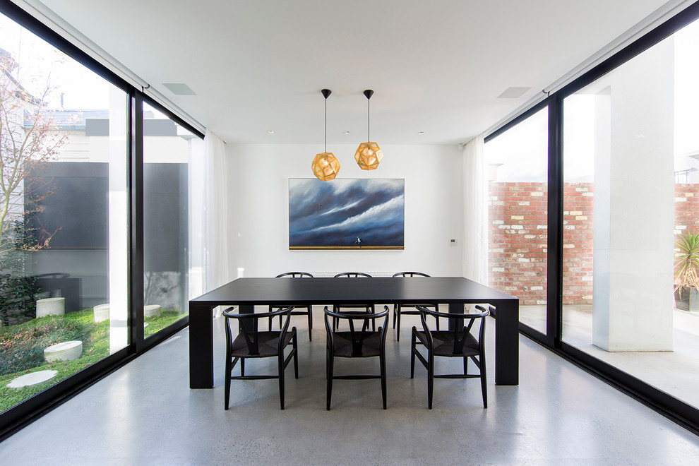 Photo of a large contemporary dining room in Melbourne with white walls and concrete flooring.
