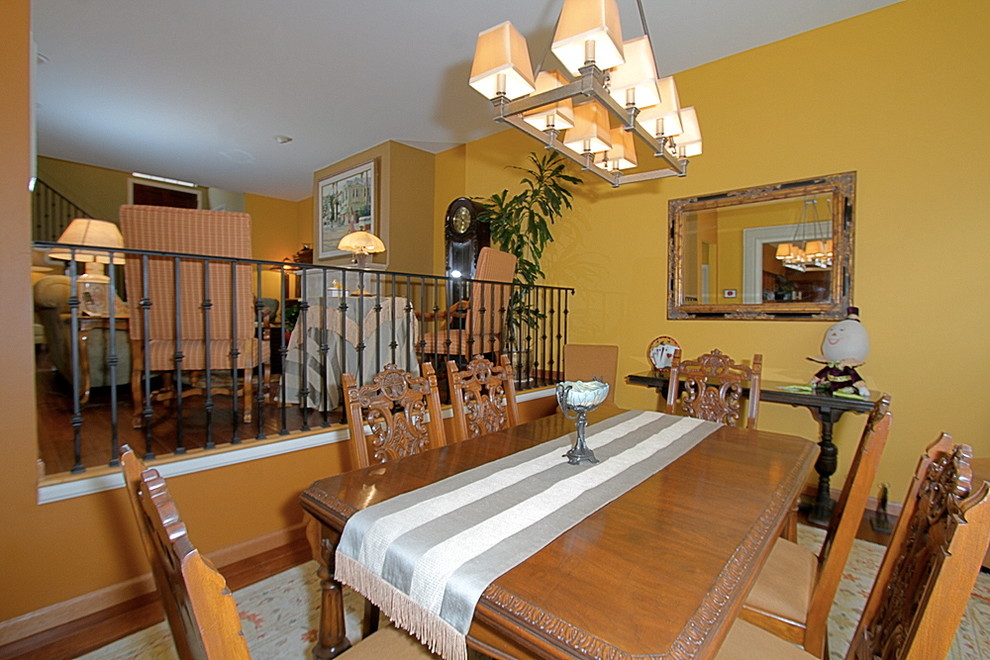 Elegant medium tone wood floor dining room photo in Other with yellow walls