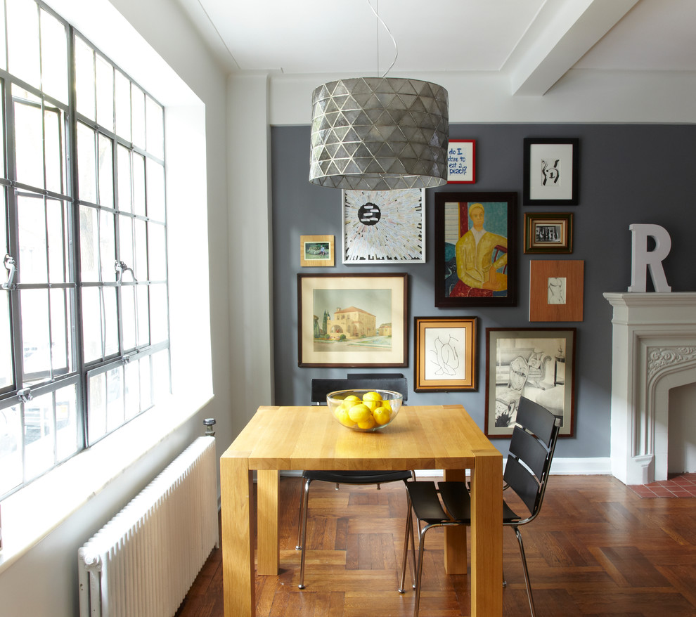Exemple d'une petite salle à manger ouverte sur le salon industrielle avec un mur gris, un sol en bois brun, une cheminée standard et un manteau de cheminée en bois.