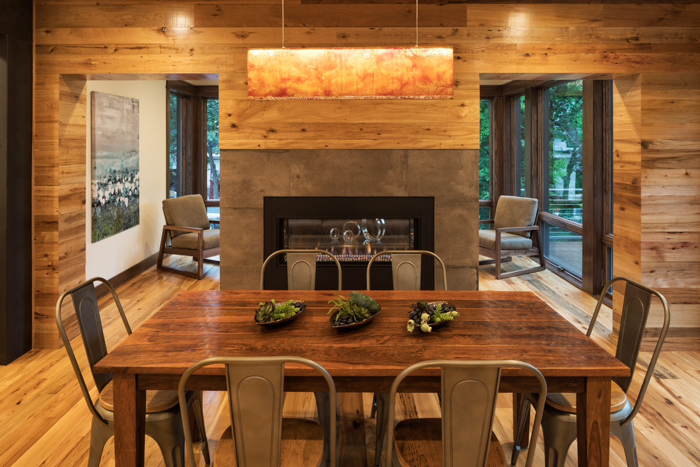 Cette image montre une salle à manger ouverte sur la cuisine chalet avec parquet clair et une cheminée double-face.