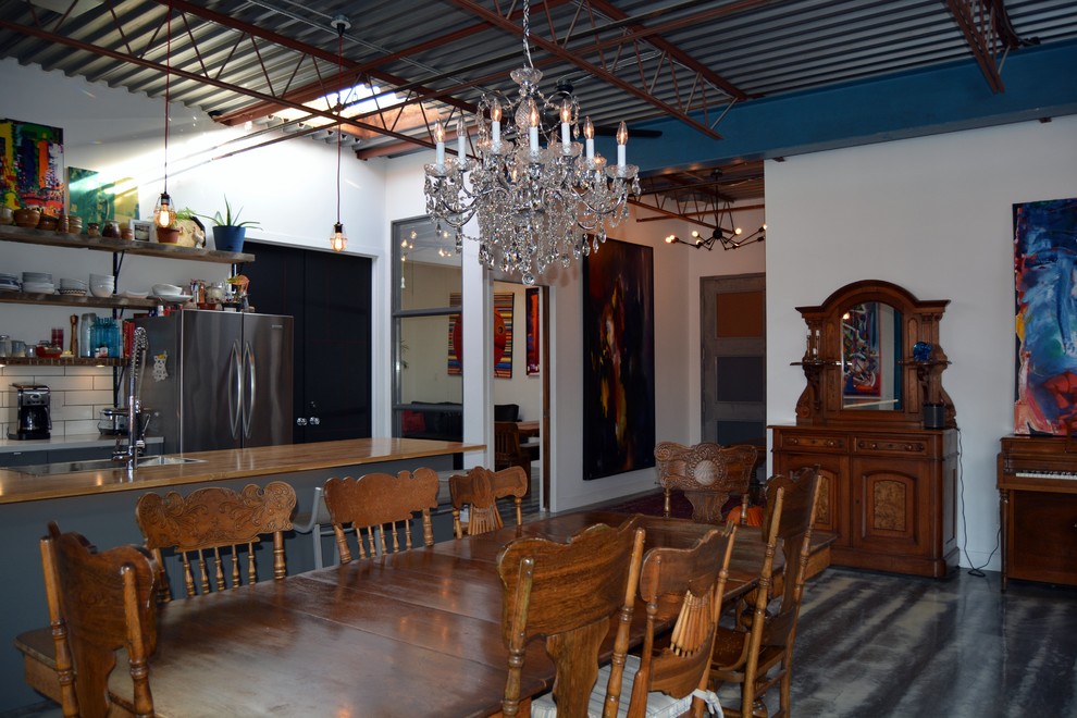 Foto di una sala da pranzo aperta verso il soggiorno industriale di medie dimensioni con pareti bianche e pavimento in cemento