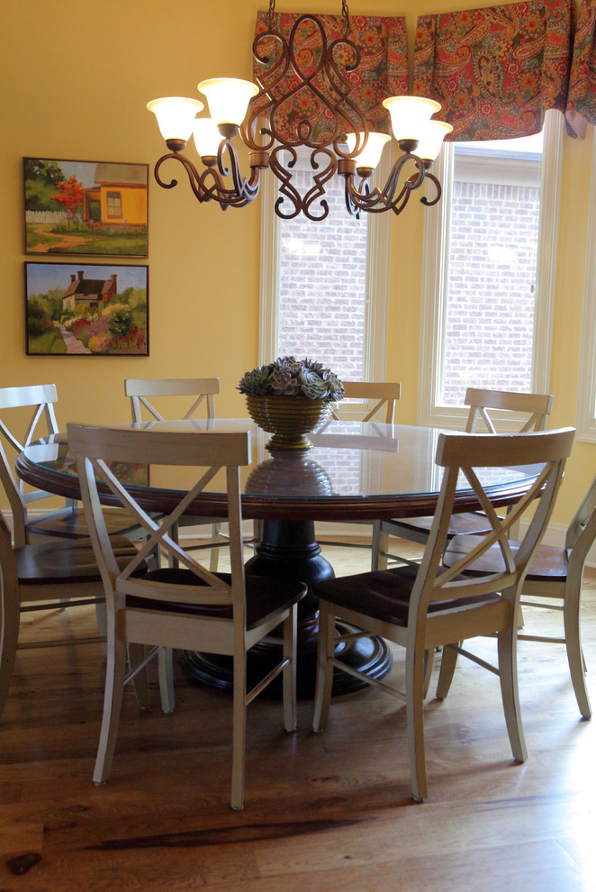 Elegant medium tone wood floor dining room photo in Other with yellow walls