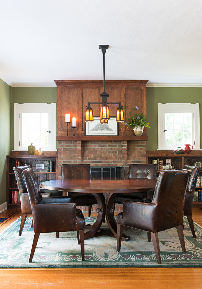 Esempio di una sala da pranzo american style con pareti verdi, pavimento in legno massello medio e cornice del camino in mattoni