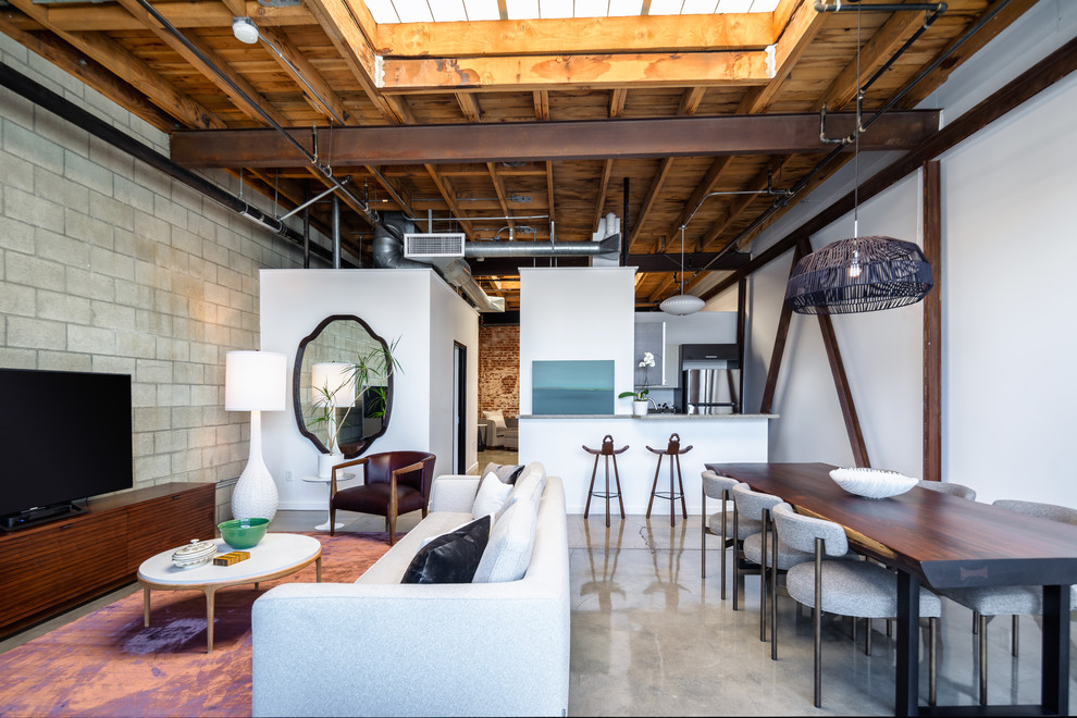 Esempio di una sala da pranzo aperta verso il soggiorno industriale con pareti bianche, pavimento in cemento e pavimento grigio