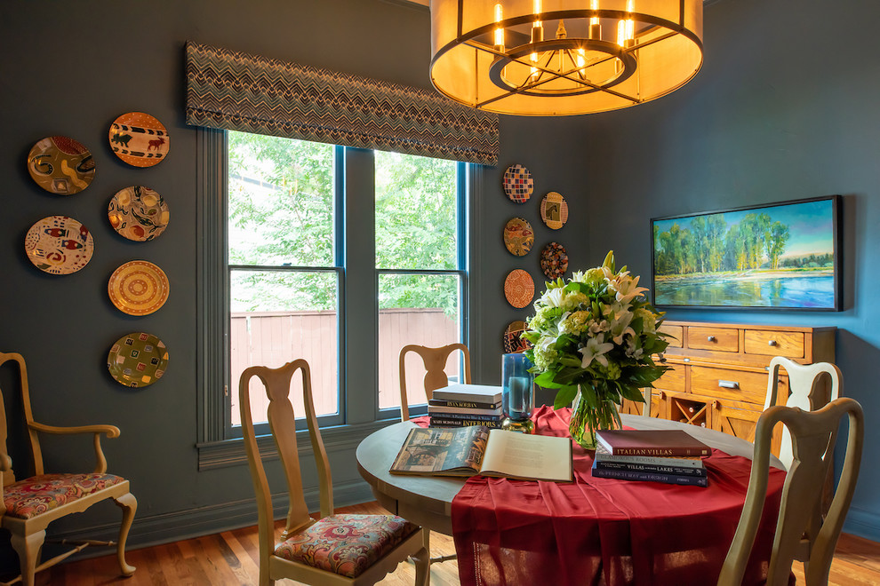 Cette image montre une salle à manger bohème fermée avec un mur bleu, un sol en bois brun et aucune cheminée.