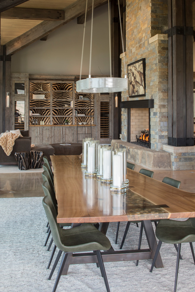 Cette photo montre une salle à manger éclectique avec sol en béton ciré et une cheminée double-face.