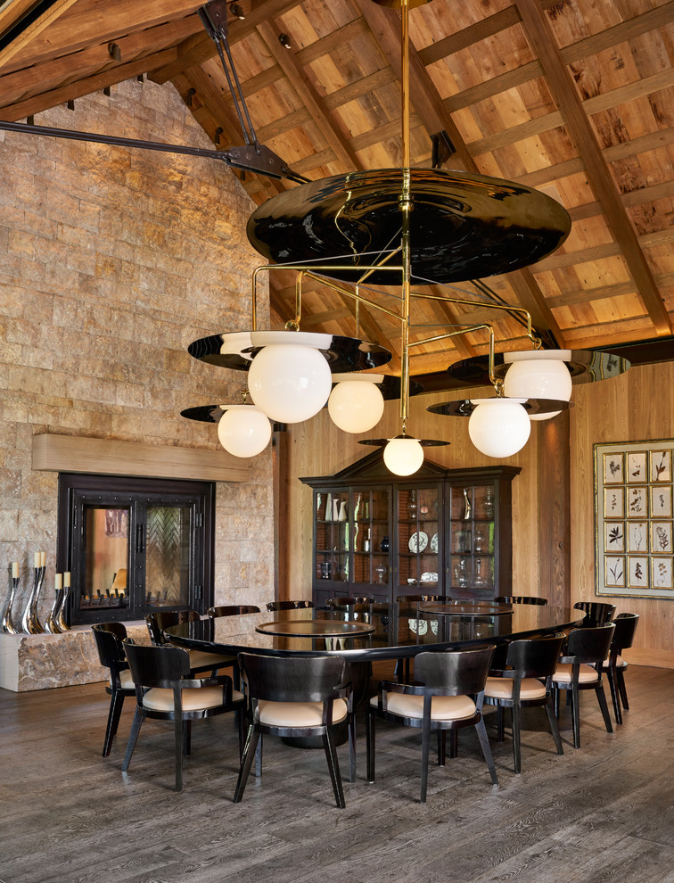 Cette photo montre une grande salle à manger ouverte sur le salon montagne avec une cheminée double-face, parquet foncé et un sol marron.