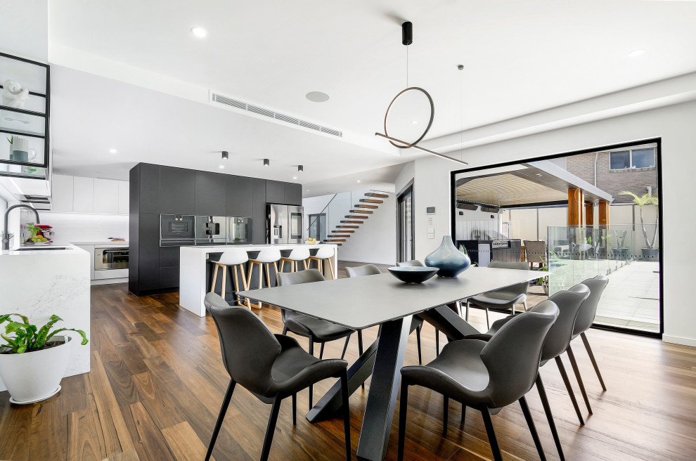 Offenes Modernes Esszimmer mit weißer Wandfarbe, dunklem Holzboden und braunem Boden in Melbourne