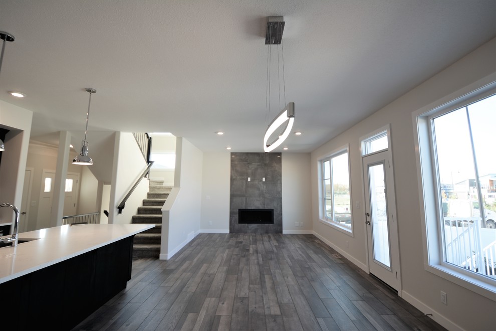 Mittelgroße Moderne Wohnküche mit grauer Wandfarbe, Laminat, Kamin, gefliester Kaminumrandung und grauem Boden in Calgary
