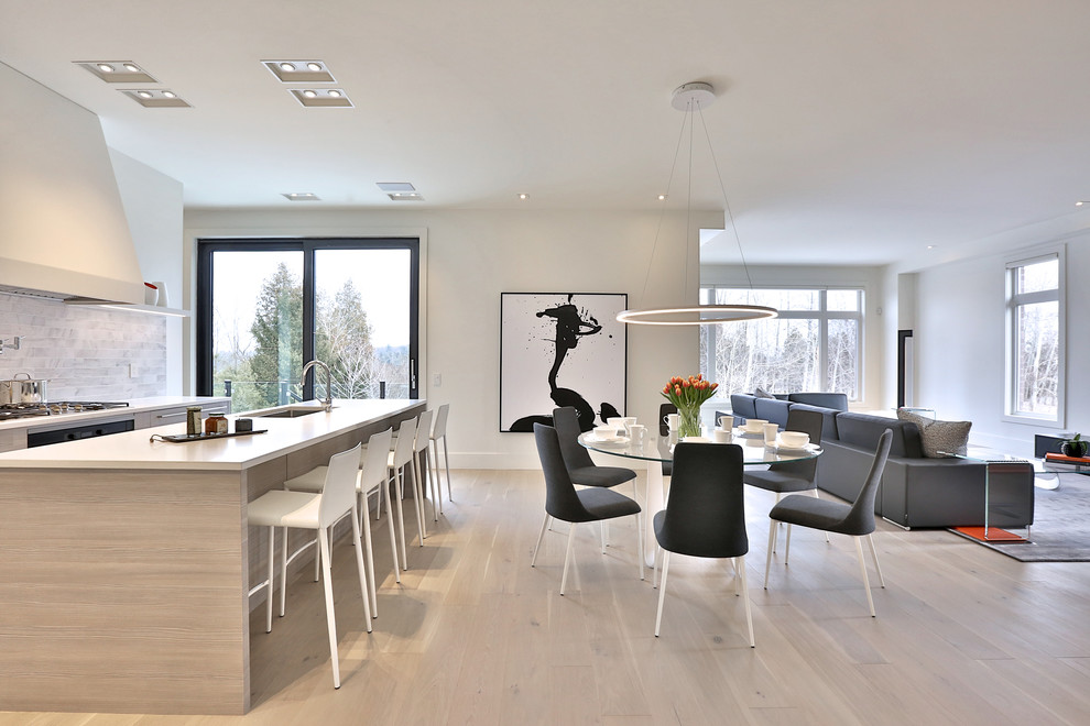 Expansive modern dining room in Toronto with white walls, light hardwood flooring, a ribbon fireplace and a stone fireplace surround.