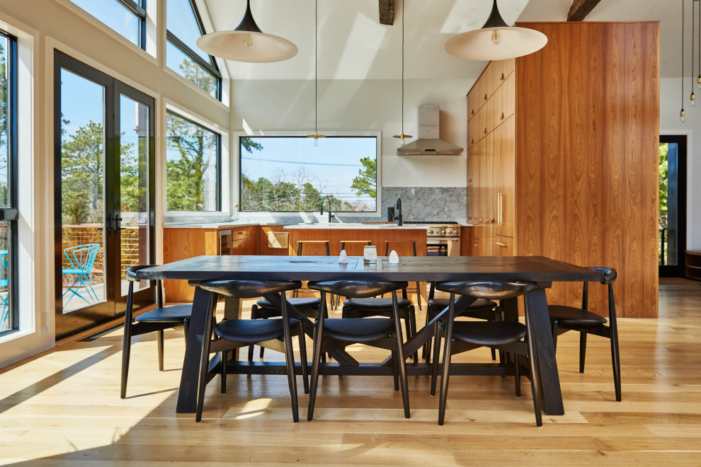 Immagine di una grande sala da pranzo aperta verso la cucina design con pareti bianche, parquet chiaro e soffitto a volta