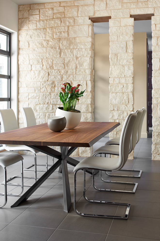 Cette image montre une salle à manger minimaliste fermée et de taille moyenne avec un mur blanc, un sol en carrelage de porcelaine, aucune cheminée, un sol gris et un manteau de cheminée en pierre.