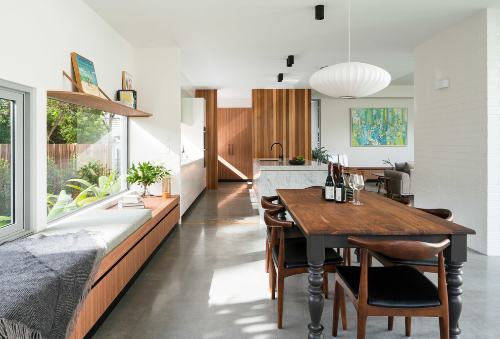 Midcentury open plan dining room in Brisbane with white walls, concrete flooring and grey floors.