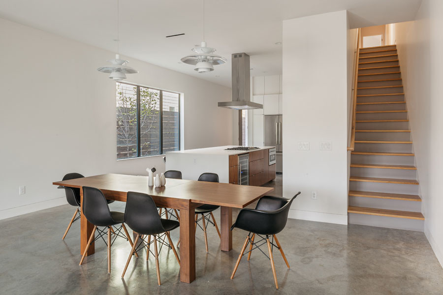 Esempio di una sala da pranzo aperta verso il soggiorno minimalista con pareti bianche, pavimento in cemento e nessun camino