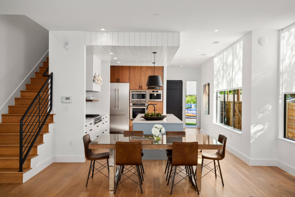 Cette image montre une salle à manger ouverte sur la cuisine design de taille moyenne avec un mur blanc, parquet clair et un plafond en lambris de bois.