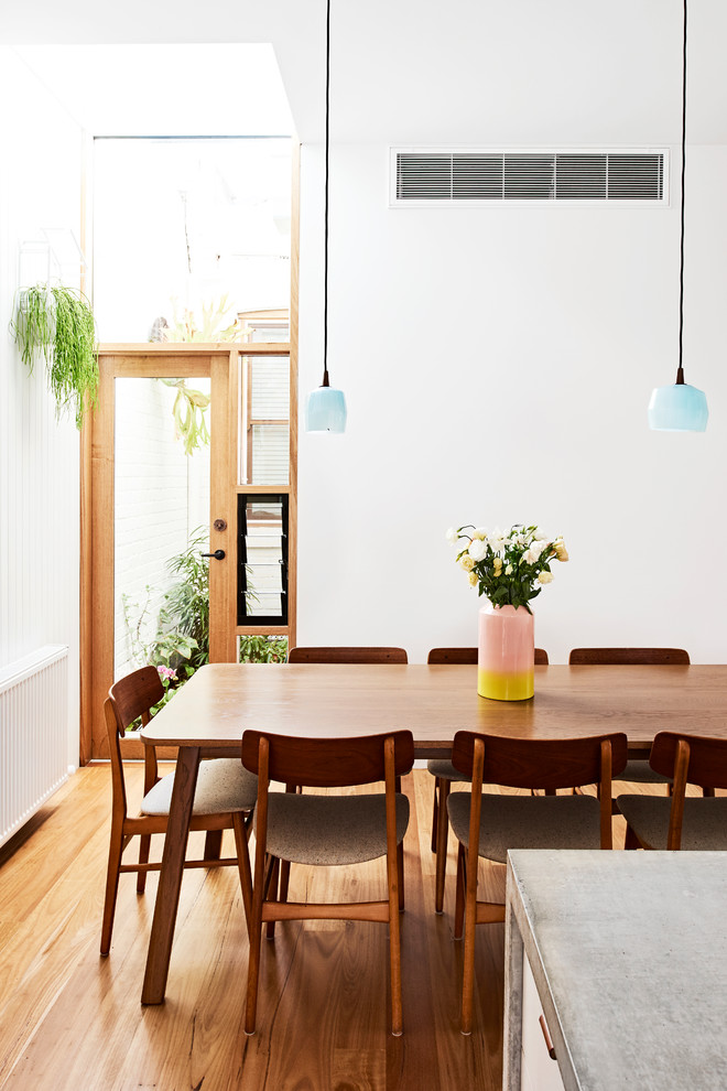 Cette photo montre une grande salle à manger ouverte sur la cuisine tendance avec un mur blanc, parquet clair et aucune cheminée.