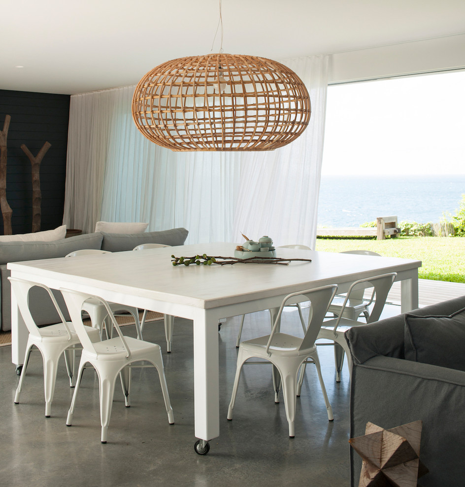 Idee per una sala da pranzo aperta verso il soggiorno costiera con pavimento in cemento e pavimento grigio