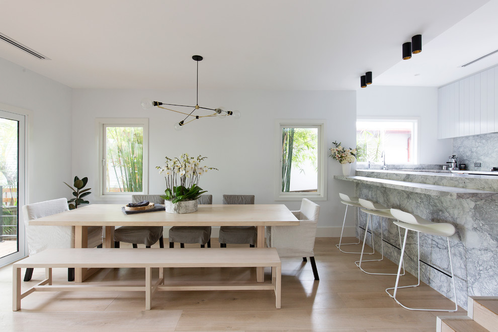 This is an example of a contemporary kitchen/dining room in Sydney with white walls, light hardwood flooring and beige floors.