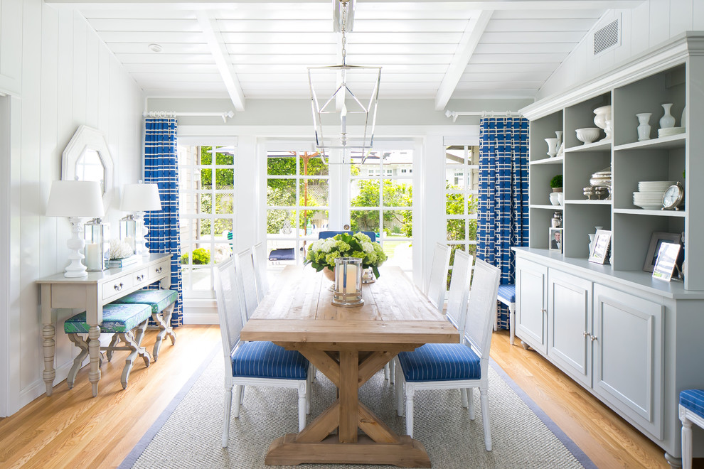 Immagine di una sala da pranzo costiera con pareti bianche e pavimento in legno massello medio