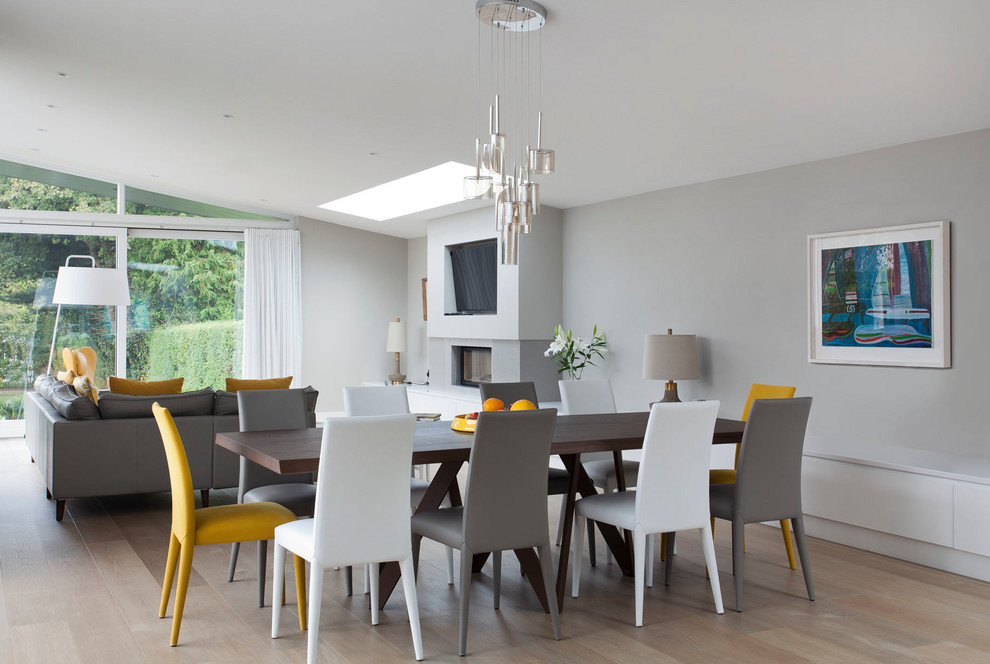 Réalisation d'une salle à manger design avec un mur gris, parquet clair, un sol beige et une cheminée standard.