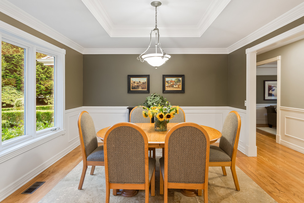 This is an example of a classic enclosed dining room in Seattle with green walls and medium hardwood flooring.