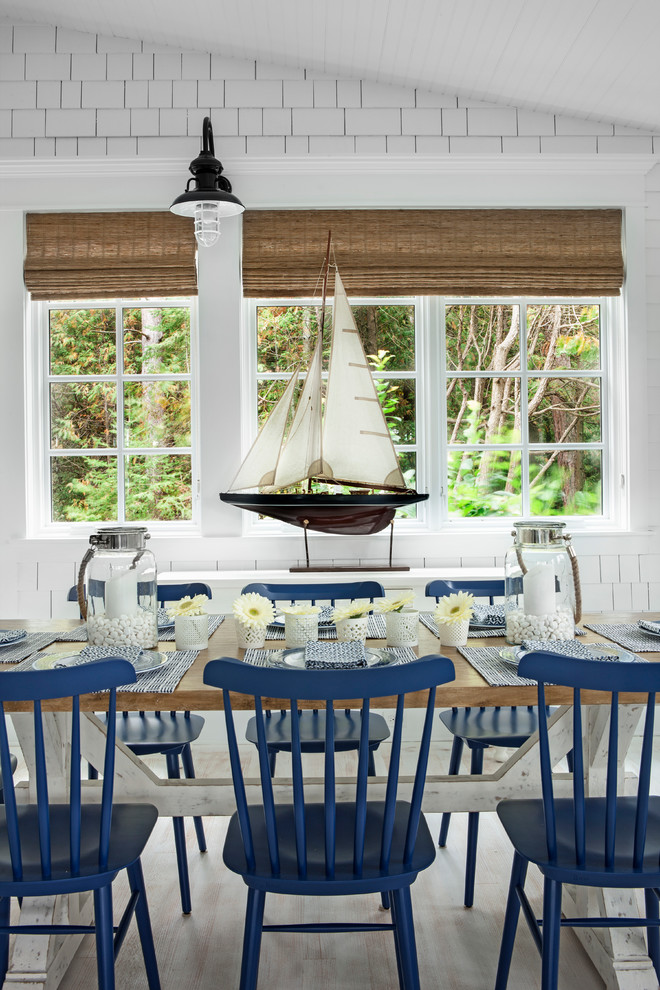 Ejemplo de comedor costero con paredes blancas y suelo de madera clara