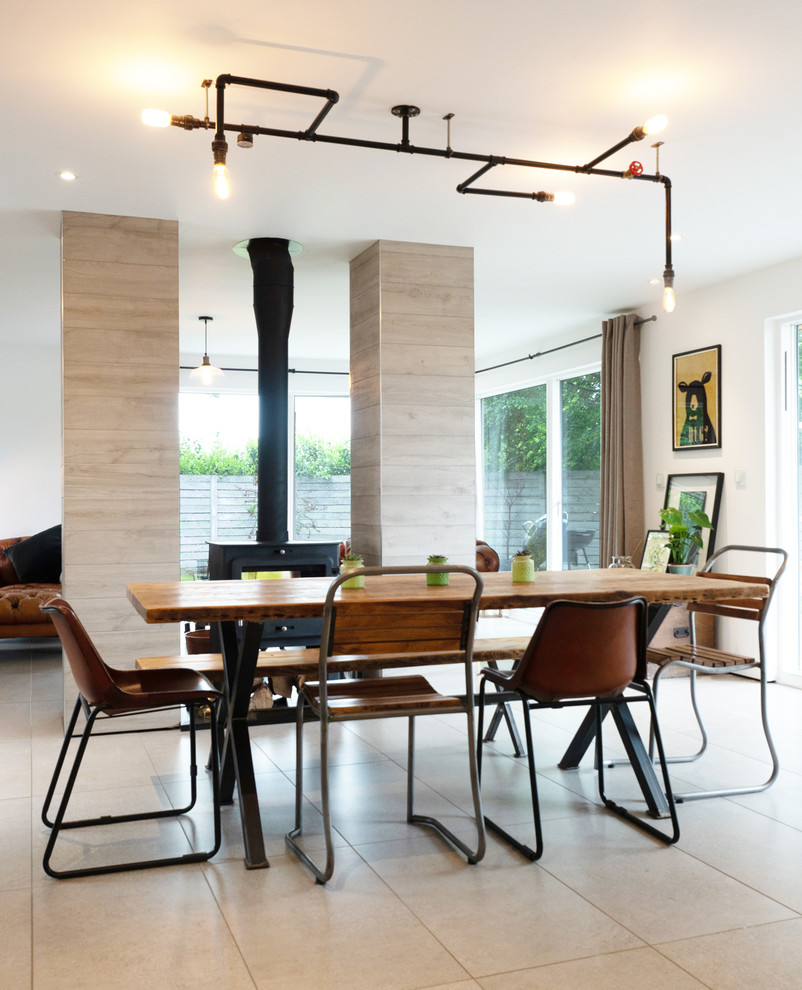 Photo of a medium sized urban open plan dining room in West Midlands with white walls, limestone flooring, a wood burning stove and a tiled fireplace surround.