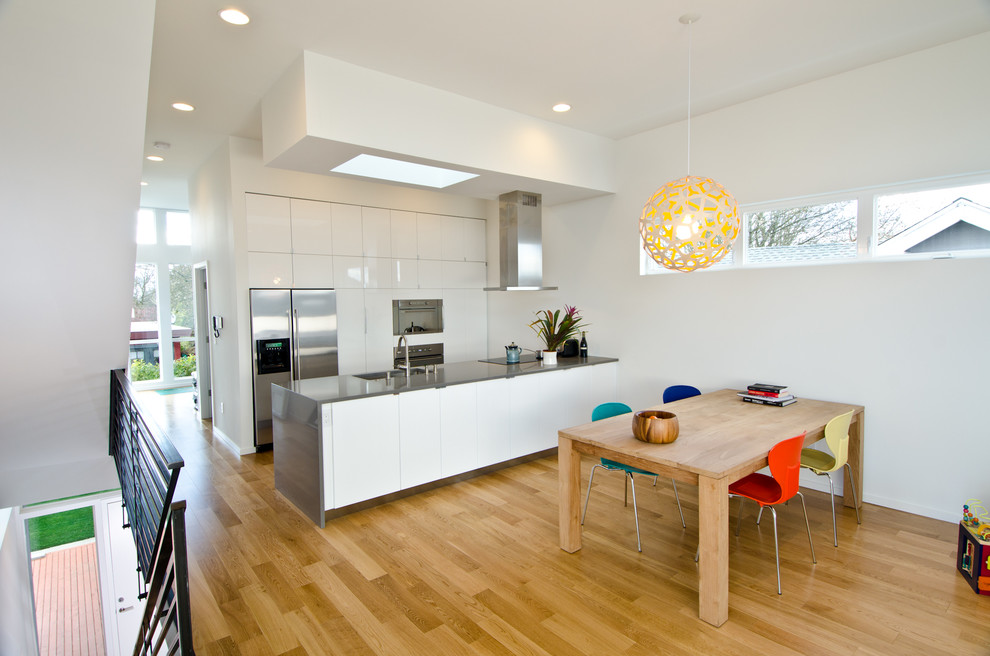 На фото: кухня-столовая среднего размера в современном стиле с белыми стенами и светлым паркетным полом без камина с