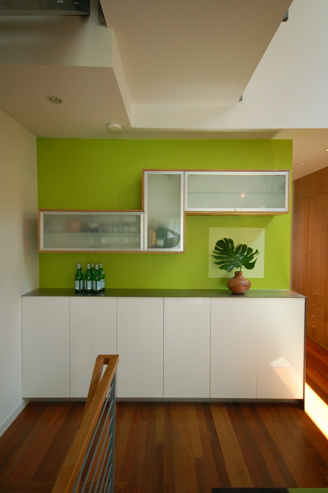 Foto di una sala da pranzo aperta verso il soggiorno minimalista con pareti verdi e parquet scuro