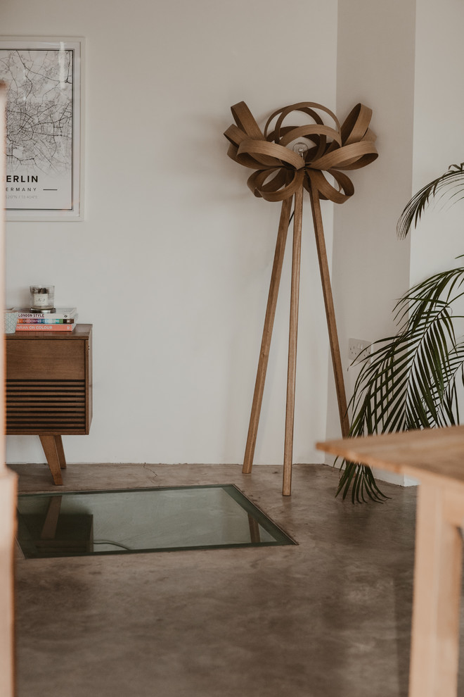 Foto di una sala da pranzo aperta verso il soggiorno eclettica di medie dimensioni con pareti bianche, pavimento in cemento, stufa a legna e pavimento grigio