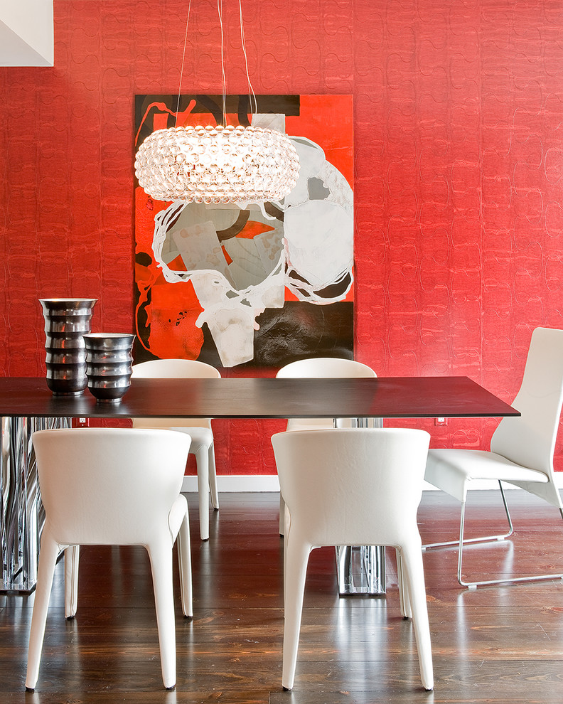 Réalisation d'une salle à manger design avec un mur rouge et parquet foncé.