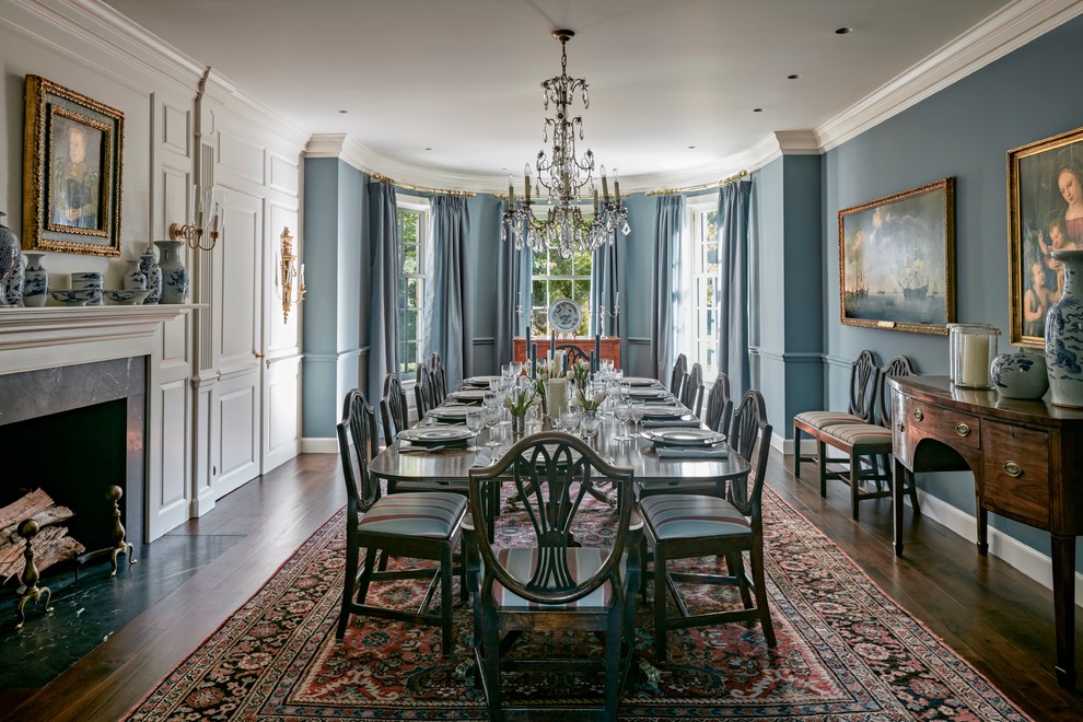 Immagine di una grande sala da pranzo classica chiusa con pareti blu, parquet scuro, camino classico e cornice del camino piastrellata